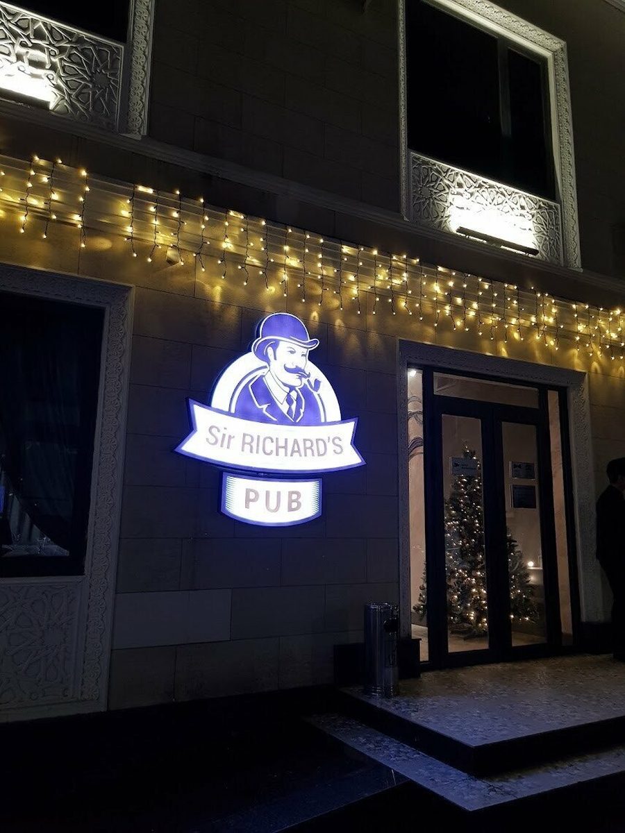 Светящаяся вывеска Sir Richard's Pub на фасаде здания вечером